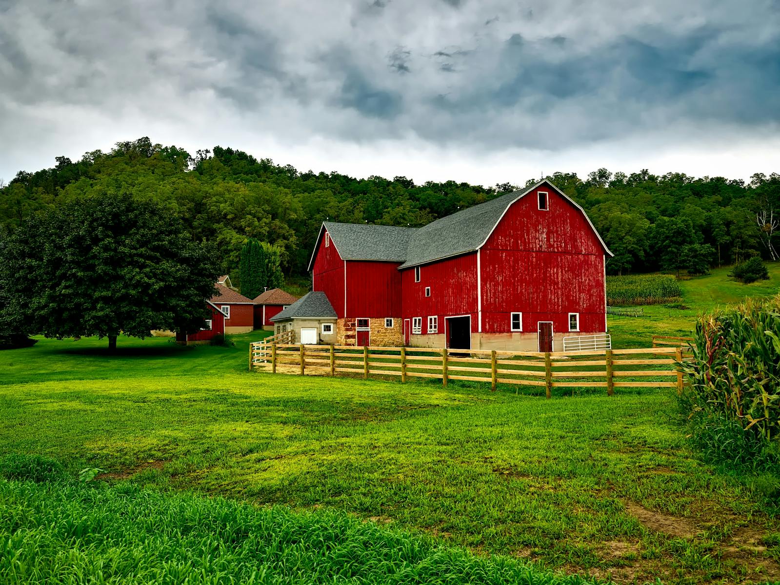 Vibrant red barn amidst lush greenery and cloudy skies in Wisconsin.